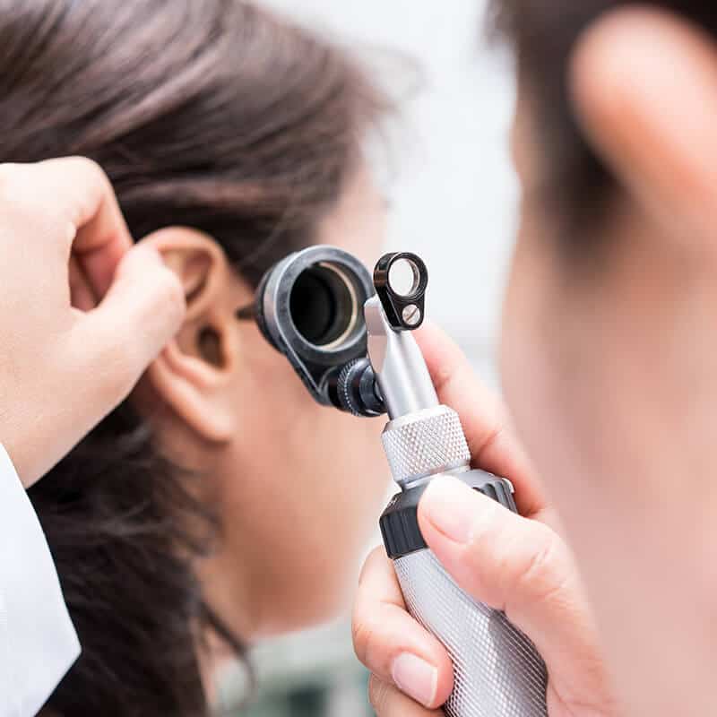 Hearing Aid Evaluation | Doctor checking a patient’s ear with an otoscope